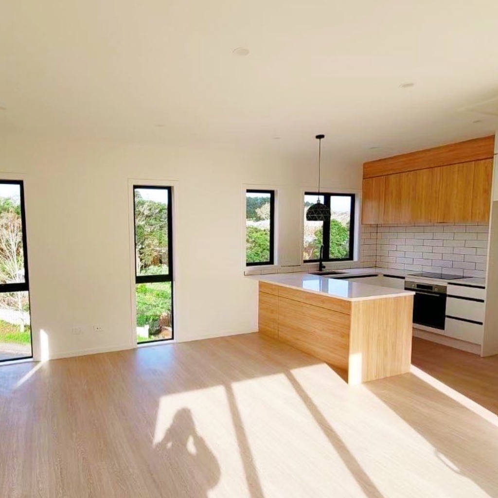 Modern kitchen with wooden cabinets, island, and large windows overlooking greenery.