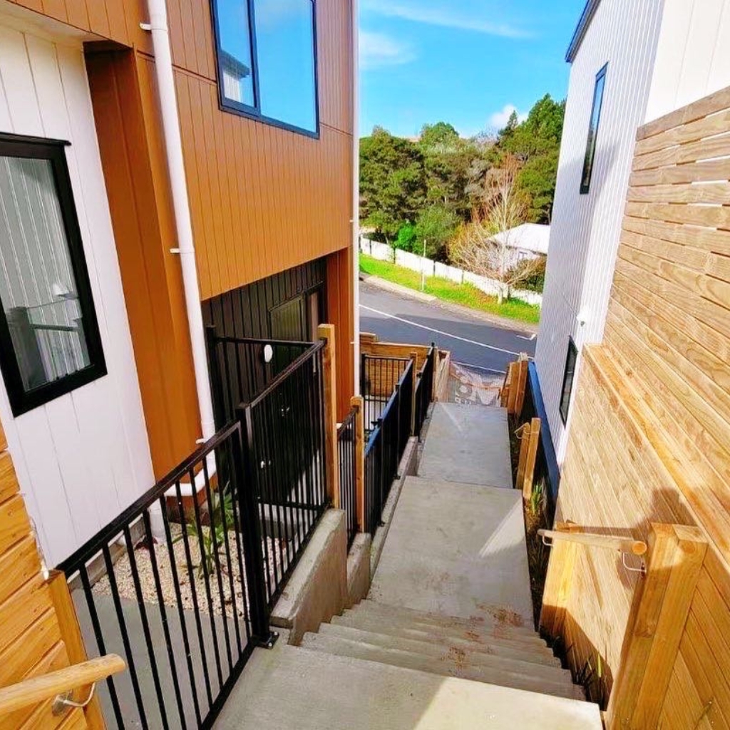 Outdoor staircase between modern buildings, leading to a street.