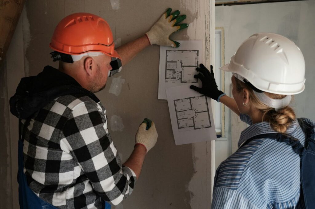 Two construction workers reviewing home renovation blueprints.
