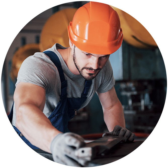 Worker in orange helmet operating machinery in industrial setting.