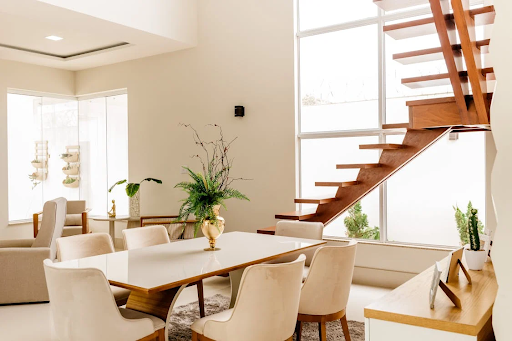 Modern dining room with wooden staircase and large windows.