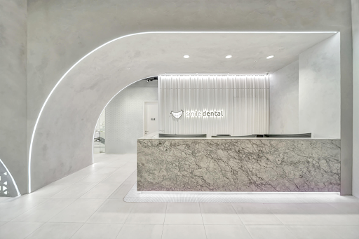 Modern dental office reception with marble desk and sleek lighting.