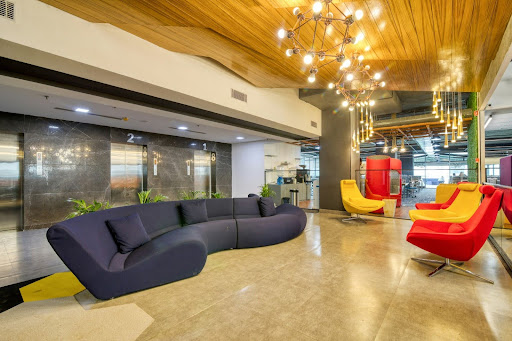Modern office lounge with colorful seating and contemporary lighting.