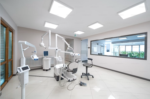 Modern dental surgery room with equipment and large windows.