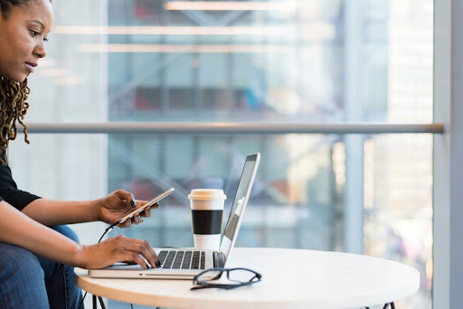 Person working on a laptop with a smartphone and coffee cup nearby.