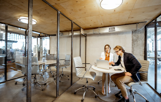 Two people working at a table in a modern office space.