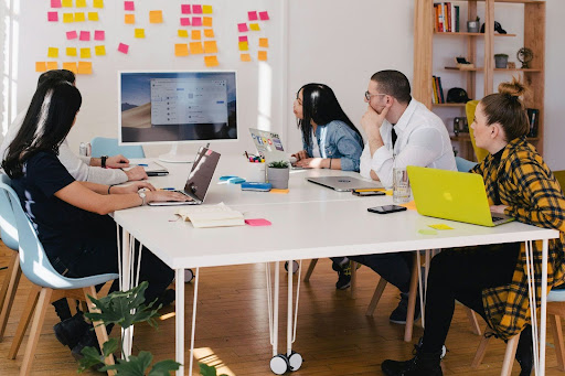 People collaborating at a table with laptops and sticky notes.